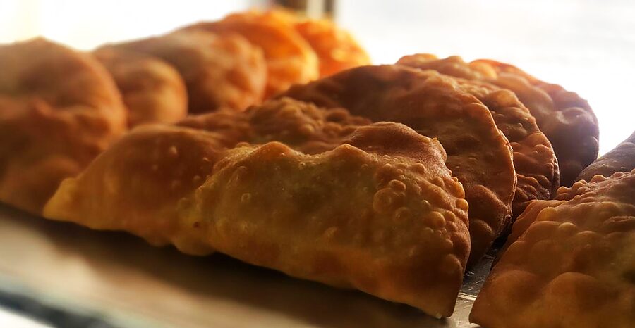 Row of golden pastechi fresh from the fryer at an Aruban snack stand